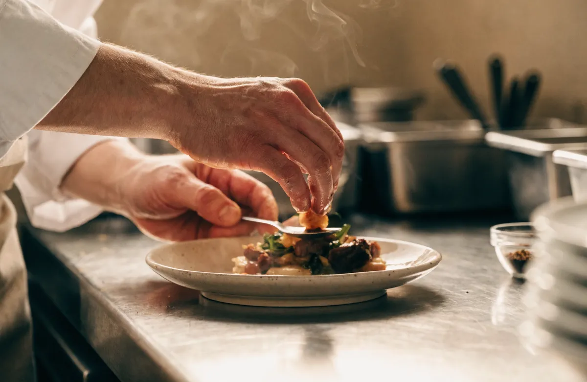 Mains d'un cuisinier dressant une assiette